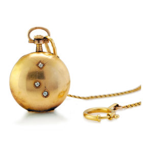 9. Zegarek kieszonkowy zdobiony motywem négligée z dewizką, pocz. XX w., Szwajcaria, Louis Grisel złoto 14 K, 3 szt. diamentów ł. ~ 0,10 ct, numer koperty: 150098, dewizka: złoto pr. 0,585, zapięcia złoto pr. 0,750; masa brutto: 34,86 g; wym. koperty: 3 x 4 cm.